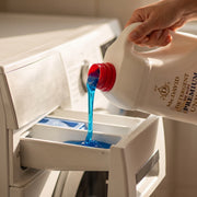 Detergent lichid Mc. David albastru și vâscos, turnat din bidonul de 5 litri în sertarul mașinii de spălat